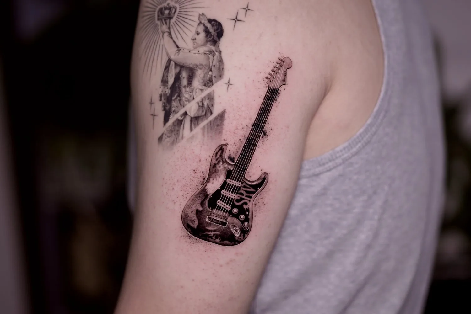 Guitar tattoo on the upper arm by Moussa in Shanghai